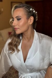 Maquillaje de novia en Valencia con piel luminosa, ondas laterales y adornos florales, estilo elegante y romántico para boda